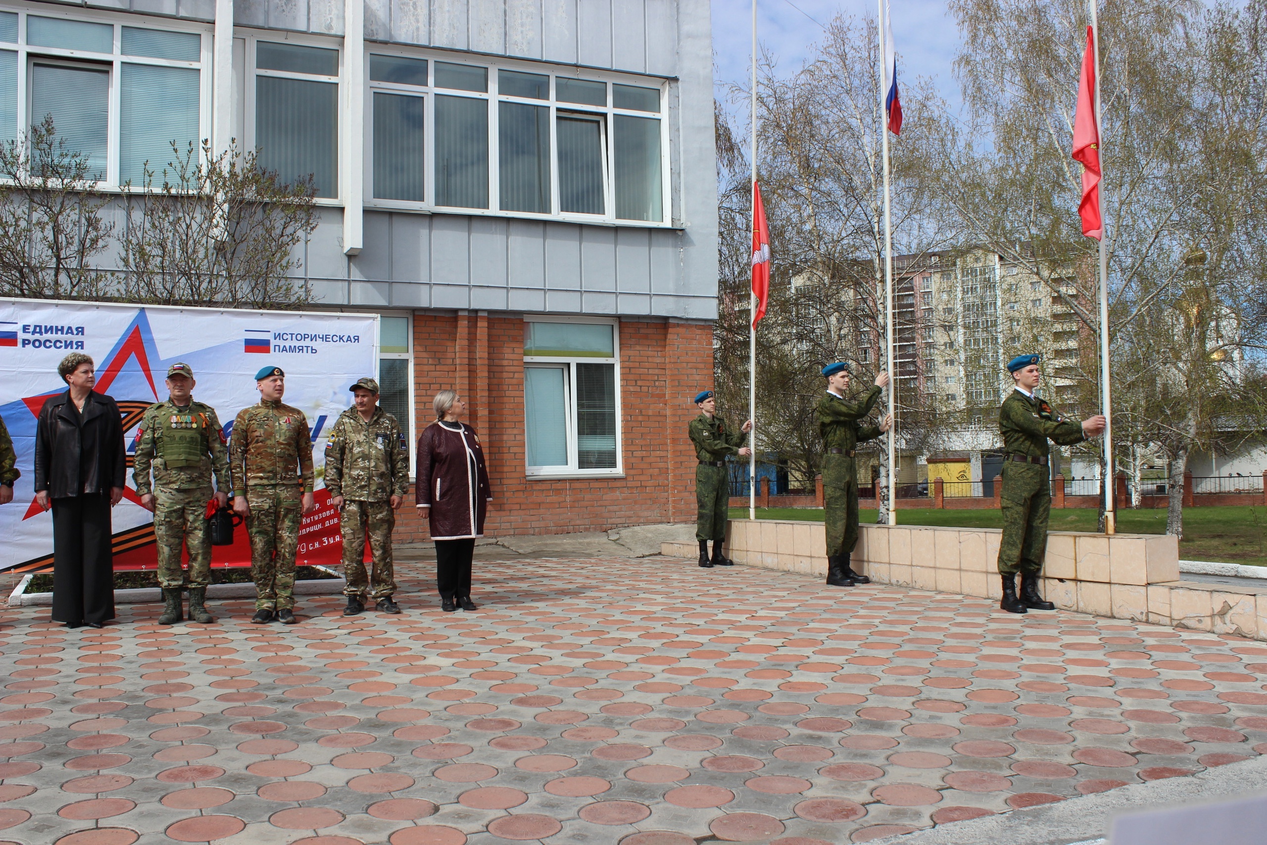 Гости и администрация техникума смотрят на поднятие флагов