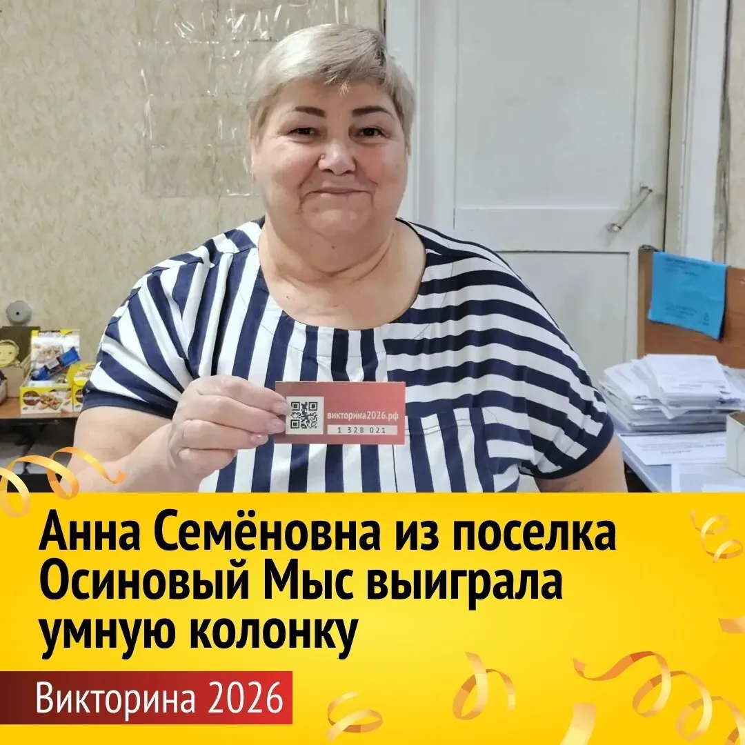 Женщина старшего возраста в полосатой футболке держит в руках карточку с QR-кодом и надписью «викторина2026.рф». Она находится в помещении с документами на столе. Внизу текст: «Анна Семёновна из поселка Осиновый Мыс выиграла умную колонку. Викторина 2026».