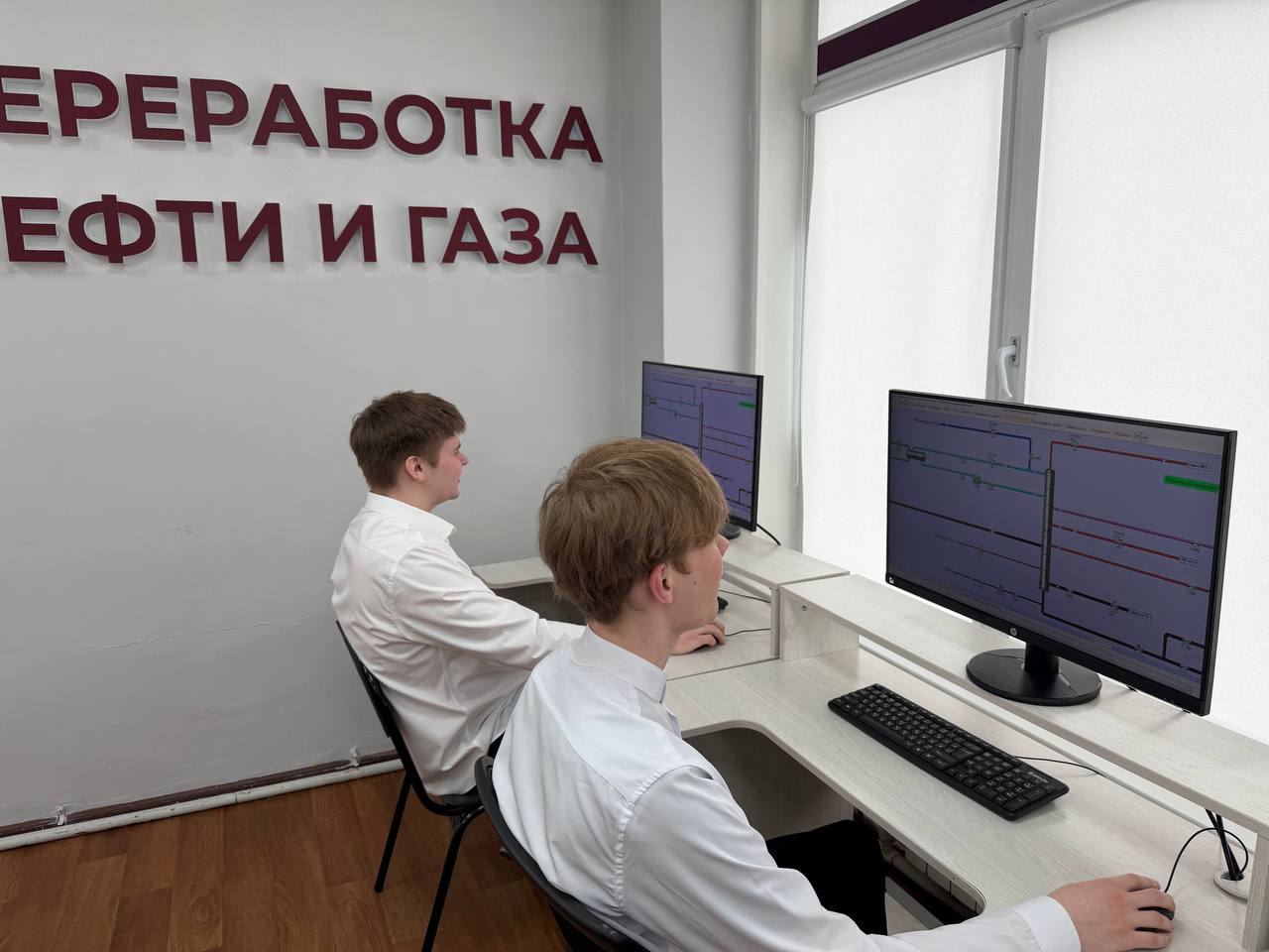 В этом изображении двое сотрудников, также в белых рубашках, работают за компьютерами. На стене написано «Переработка нефти и газа». Экран монитора показывает графическую информацию. Окна закрыты шторами, что создает светлую, но тихую атмосферу.