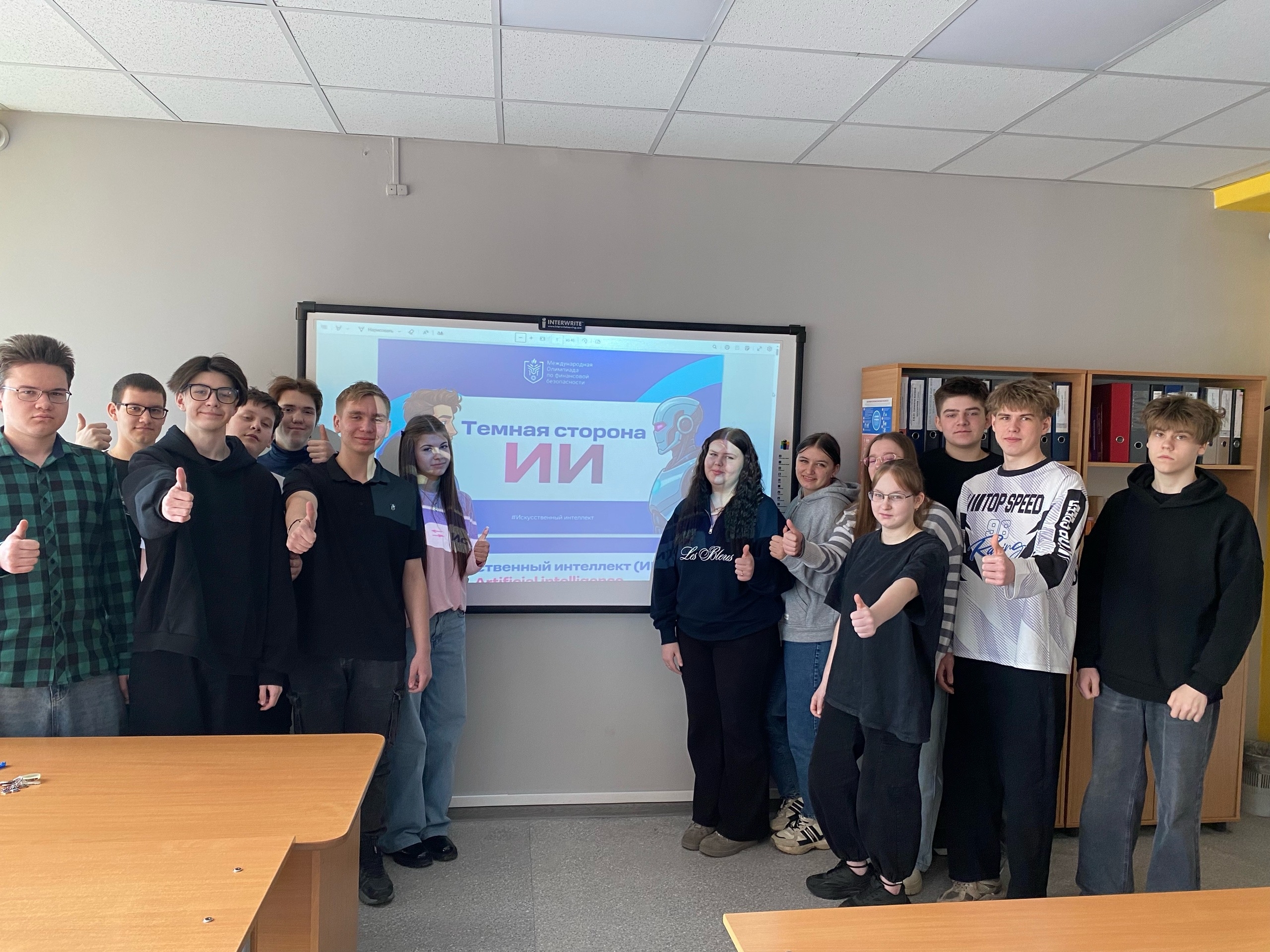 группа из четырнадцати человек стоит перед экраном, но теперь они показывают жест "лайк" с поднятыми большими пальцами. Все участники одеты в темную одежду, некоторые в шарфах, а настройки освещения остается таким же. На стене снова видна презентация с надписью "Темная сторона ИИ", но с более яркими яркими цветами. Столы видны в передней части изображения, создавая учебную атмосферу.