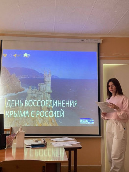 Студент выступает с докладом на фоне экрана с презентацией "День воссоединения крыма с Россией"