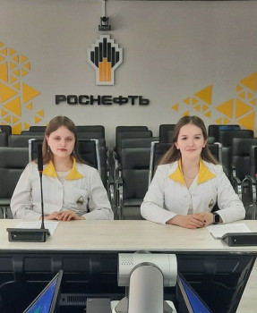 Два студента за рабочим местом, на фоне логотип Роснефть 